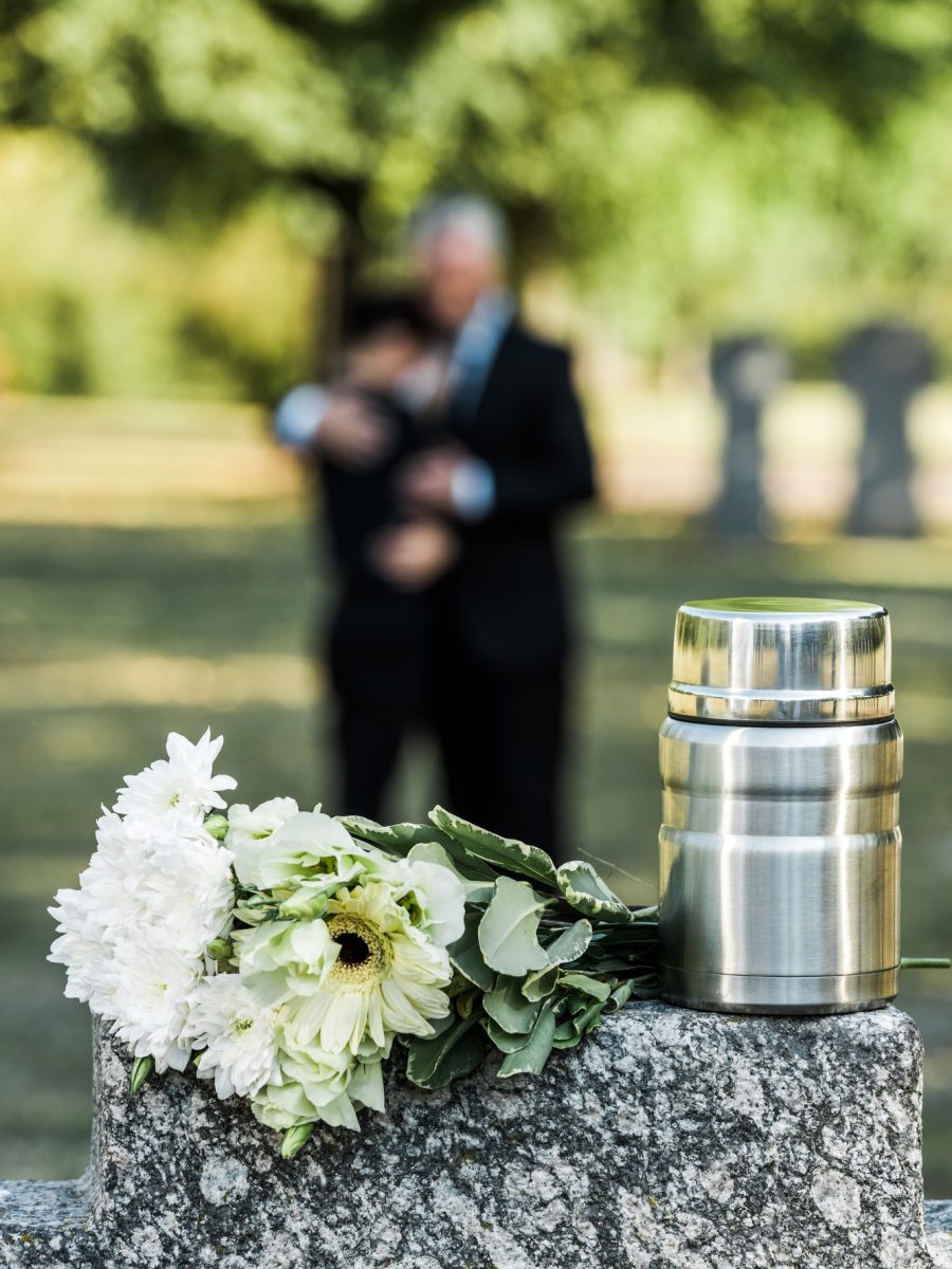 selective focus of flowers and mortuary urn on tombstone